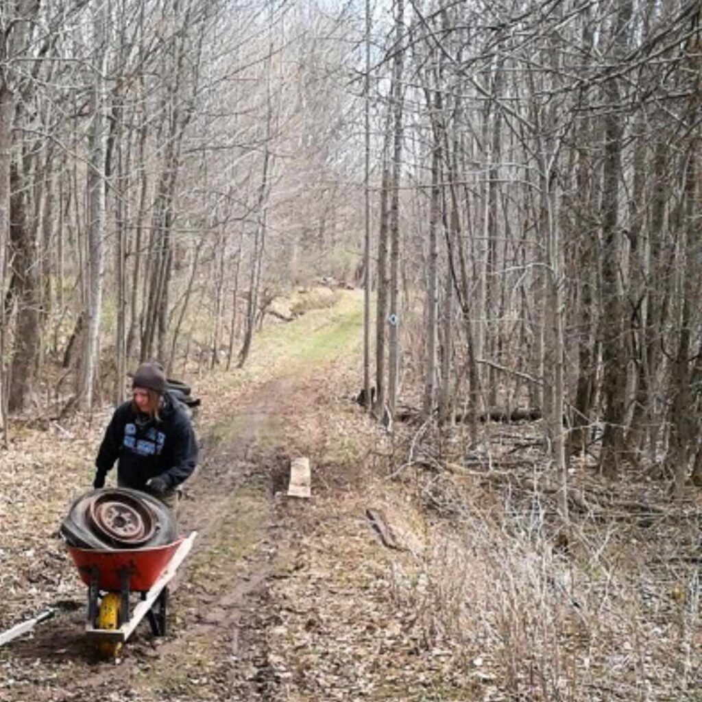 Volunteer removing legacy waste in a wheelbarrow from Kawartha Land Trust's Ingleton-Wells Property